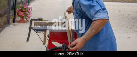 Image d'un artisan qui fait des coupes dans une poutre en bois avec un banc de scie. Travaux de menuiserie DIY. Banque D'Images