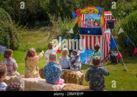 Children watching a Punch and Judy show at Wingfield summer fete. Suffolk, UK. Stock Photo