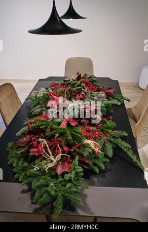D'en haut de la décoration du nouvel an de branches de sapin avec des feuilles rouges et des fleurs placées sur la table Banque D'Images