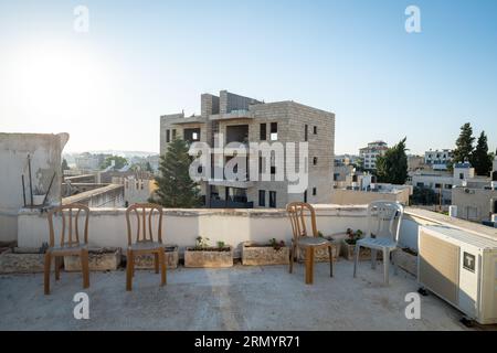 Shuafat, Jerusalem – 21 July 2018: White Stone Building Under Construction Rustic Terrace on a Roof Top with Plastic Chairs and Flower Pots Stock Photo
