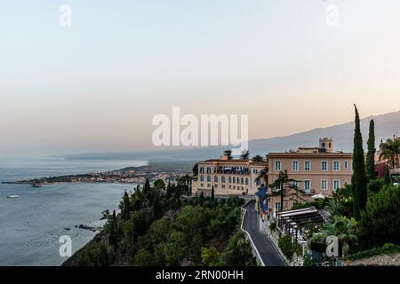 Bâtiment d'hôtel à Taormina avec hébergement pour les touristes près de la côte au coucher du soleil Banque D'Images