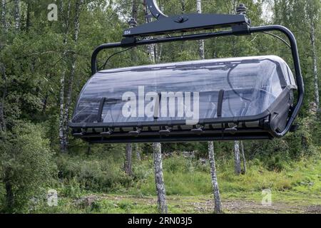 Close-up of a chairlift cab on the background of mountains and forests. Cable car trip to viewpoints in the mountains. During the trip by cable car To Stock Photo