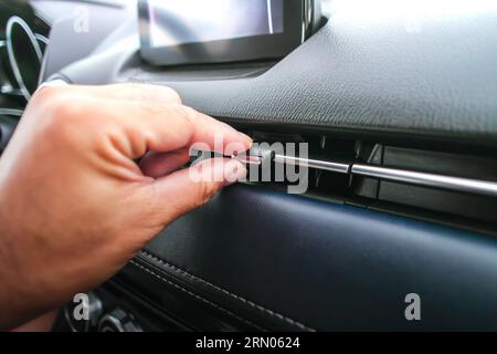 La main du conducteur ajuste la direction du vent de l'aérateur dans la voiture, bouton de réglage de la direction du système de climatisation dans la voiture. Banque D'Images