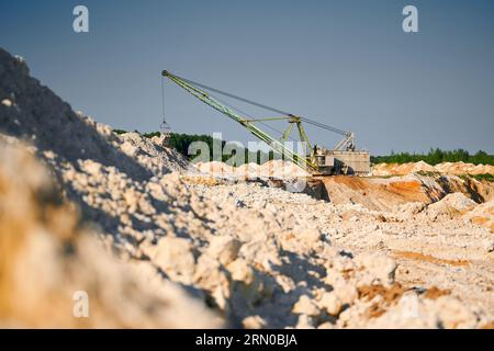 La pelle de marche fonctionne près des rangées de pieux dans la fosse minière Banque D'Images
