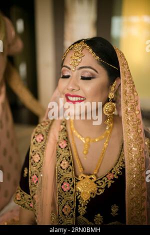 La mariée népalaise radieuse, drapée dans un saree rouge resplendissant, accueille chaleureusement son marié avec une joyeuse anticipation de leur Union, une image de l'intemporel. Banque D'Images