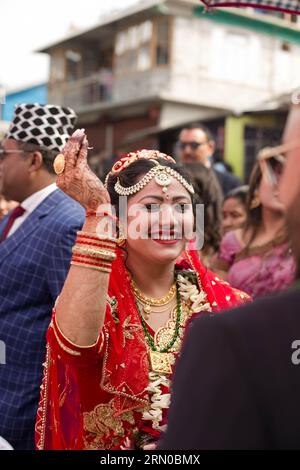 La mariée népalaise radieuse, drapée dans un saree rouge resplendissant, accueille chaleureusement son marié avec une joyeuse anticipation de leur Union, une image de l'intemporel. Banque D'Images