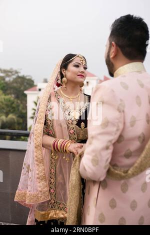 Une belle mariée népalaise accueille le marié avec bonheur et se regarde dans les yeux, se tenant la main. Banque D'Images