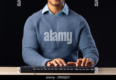 Homme d'affaires biracial utilisant le clavier avec l'espace de copie sur fond noir Banque D'Images