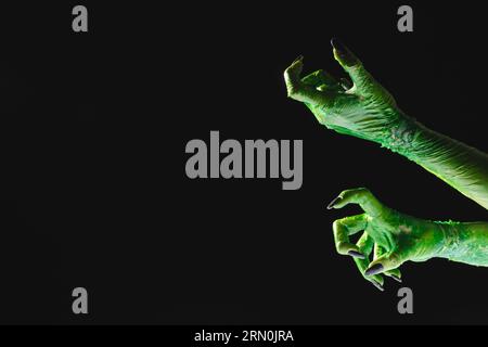 Mains de monstre vert avec des ongles noirs atteignant sur fond noir Banque D'Images
