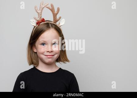 Christmas portrait of Happy child girl in Xmas hair band Santa's reindeer on white background Stock Photo