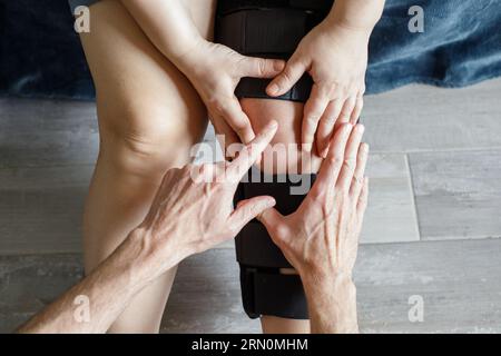 Thérapeute qui pose une genouillère sur la jambe d'une patiente Banque D'Images