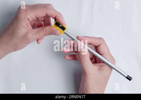 Affûtage du crayon. Mains féminines avec crayon et taille-crayon Banque D'Images