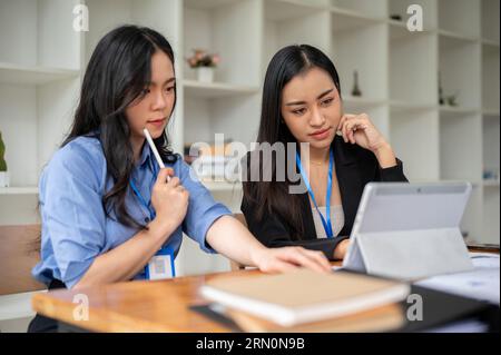 Deux comptables ou femmes d'affaires asiatiques professionnelles se concentrent sur un projet, brainstorming et analyse des données financières dans le bureau ensemble Banque D'Images