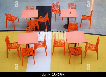 Une photo en grand angle de chaises et de tables colorées vibrantes sur le sol jaune et bleu Banque D'Images