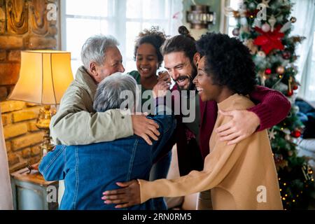 Famille pluriethnique de longue durée et gaie en s'amusant tout en célébrant Noël ensemble à la maison. Banque D'Images