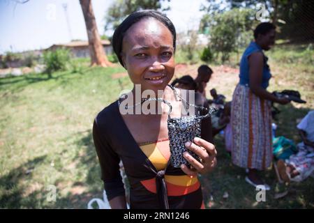 Farai Chinhoyi montre une pochette de téléphone cellulaire fabriquée à partir de plastique recyclé dans un atelier de la polyclinique de Warren Park, dans la banlieue sud de Harare, Zimbabwe, le 28 novembre 2014. Chinhoyi est membre du Zee BAG, un projet générateur de revenus géré par le Friendship Bench basé à Harare, une collaboration entre le Zimbabwe AIDS Prevention Project de l'Université du Zimbabwe en collaboration avec le King s College London s Institute of Psychiatry qui fournit des services de santé mentale aux femmes victimes de violence psychologique et à celles qui vivent avec le VIH. En tissant du plastique recyclé dans divers types de choses, allant de la Banque D'Images