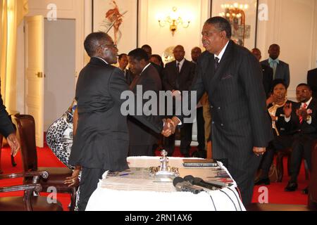 (141212) -- HARARE, 12 décembre 2014 -- Phelekezela Mphoko(R), l'une des vice-présidentes serre la main du président zimbabwéen Robert Mugabe lors de la cérémonie d'inauguration à Harare, Zimbabwe, le 12 décembre 2014. Le président zimbabwéen Robert Mugabe a remanié son cabinet et nommé neuf nouveaux ministres pour remplacer ceux qu'il avait limogés plus tôt cette semaine en raison d'allégations de complot d'assassinat. La plupart des ministres de leurs portefeuilles, y compris ceux des finances, de la défense, de la justice et des mines, ont été retenus. Les nouveaux ministres, ainsi que deux vice-présidents nouvellement nommés Emmerson Mnangagwa et Phelekeze Banque D'Images