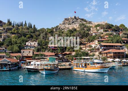 Village et château de Simena vu d'un bateau touristique arrivant, Simena, Kalekoy, Turquie Banque D'Images