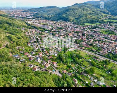 Panorama aérien de Buhl et Guebwiller dans la vallée de Florival, Haut-Rhin, Alsace : villages ensoleillés au milieu de collines boisées sous ciel bleu, été à Fran Banque D'Images