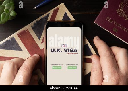 Concept de demande de visa britannique : l'homme remplit un formulaire de demande de visa britannique sur son smartphone Banque D'Images
