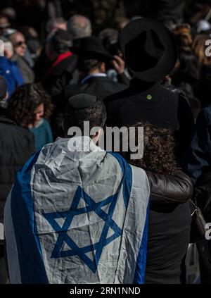 (150113) -- JÉRUSALEM, 13 janvier 2015 -- Un homme avec le drapeau national israélien sur les épaules assiste à une cérémonie funéraire pour les quatre victimes de l'attaque d'un supermarché parisien au cimetière Givat Shaul, à la périphérie de Jérusalem, le 13 janvier 2015. Les dirigeants israéliens et une multitude de personnes en deuil se sont réunis mardi avec les familles de quatre victimes juives de l'attaque terroriste de la semaine dernière contre un supermarché casher de Paris pour une cérémonie funéraire solennelle dans un cimetière de Jérusalem. Yoav Hattab, Yohan Cohen, Philippe Braham et François-Michel Saada, ont été abattus vendredi lors d’une prise d’otage sur Hyper Casher Superman Banque D'Images