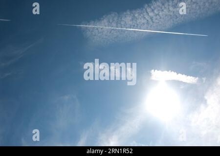 Nuages Cirrus et longue rangée de traînées d'avions. Avion aérien contrail dans fond bleu de ciel nuageux. Ligne horizontale de l'avion rapide volant dans dista Banque D'Images