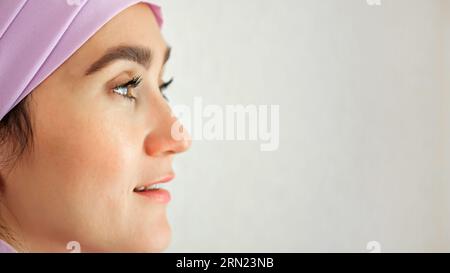 Femme musulmane avec expression excitée regarde autour en studio Banque D'Images