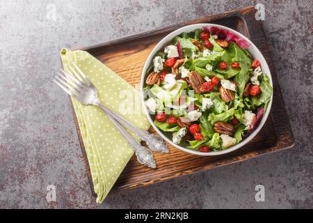 Délicieuse salade fraîche avec laitue en feuilles, cerises séchées, fromage gorgonzola, pacanes habillées de sauce vinaigrette en gros plan dans un bol sur la table. Hor Banque D'Images