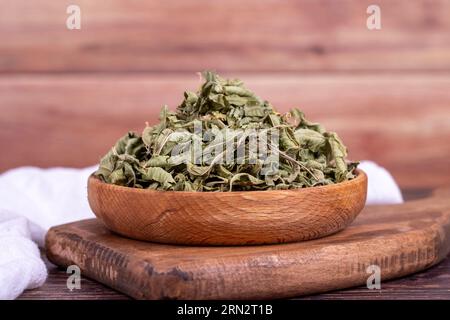 Thé au baume séché. Feuilles de thé à la mélisse séchées au soleil dans un bol en bois. phytothérapie. Gros plan Banque D'Images