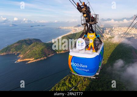 (150324) --RIO DE JANEIRO, le 24 mars 2015 -- photo fournie par le comité d'organisation des Jeux Olympiques de Rio 2016 montre la mascotte des Jeux Olympiques de Rio 2016 Vinicius debout sur un téléphérique peint avec le hashtag de 500 jours sur la célèbre montagne Sugartpain à Rio de Janeiro, Brésil. Le 24 mars marque le compte à rebours des 500 jours des Jeux Olympiques de Rio 2016. Rio2016/Alex Ferro) (SP)BRÉSIL-RIO DE JANEIRO-OLYMPIC-500 JOURS COMPTE À REBOURS XuxZijian PUBLICATIONxNOTxINxCHN Rio de Janeiro Mars 24 2015 photo fournie par le Comité d'Organisation des Jeux Olympiques de Rio 2016 montre la mascotte de Rio Olymp 2016 Banque D'Images