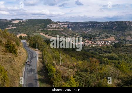 France, Aveyron, Parc naturel régional des Grands-Causses, cyclistes effectifs l'itinéraire cyclo touristique Brebis'Cyclette en pays de Roquefort, le village de Tournemire dans le cirque au pied du Causse du Larzac (vue aérienne) Banque D'Images