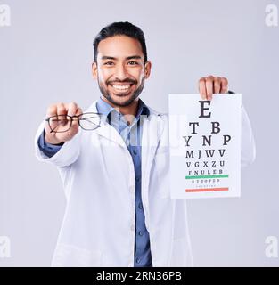 Homme, lunettes et oeil carte d'optométriste en portrait au studio isolé sur fond blanc. Visage, lunettes et ophtalmologiste heureux avec snellen Banque D'Images