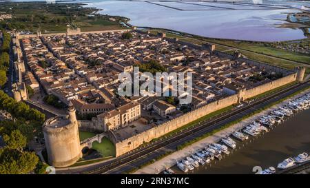 France, Gard, Aigues mortes, la cité médiévale entourée de ses remparts, la Tour de Constance et le port du Rhône au Canal de Sète au premier plan, les marais salants (Salins du midi) au fond (vue aérienne) Banque D'Images