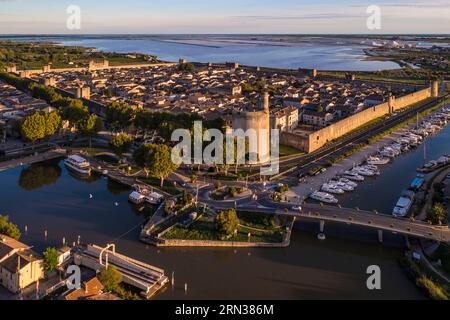 France, Gard, Aigues mortes, la cité médiévale entourée de ses remparts, la Tour de Constance et le port du Rhône au Canal de Sète au premier plan, les marais salants (Salins du midi) au fond (vue aérienne) Banque D'Images