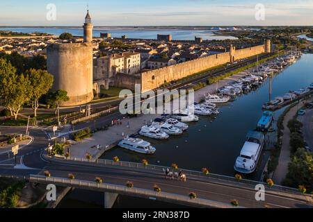 France, Gard, Aigues mortes, la cité médiévale entourée de ses remparts, la Tour de Constance et le port du Rhône au Canal de Sète au premier plan, les marais salants (Salins du midi) au fond (vue aérienne) Banque D'Images