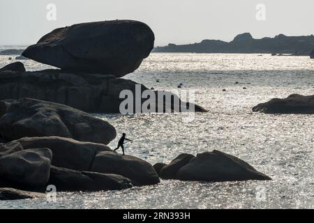 France, Côtes-d'Armor, Côte de granit Rose, Trégastel, jeune pêcheur sur les rochers devant la plage de Ker ar Vir le long du GR 34 Banque D'Images