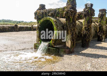 Une conduite d'eaux usées avec de l'eau se déversant sur la plage d'Abersoch, au pays de Galles Banque D'Images