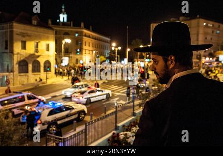 Un juif ultra-orthodoxe regarde une manifestation dans le centre de Jérusalem, le 30 avril 2015. Environ 1 000 Éthiopiens israéliens sont descendus dans les rues du centre de Jérusalem jeudi soir pour protester contre la brutalité policière et le racisme, et se sont affrontés avec les forces de police. Les manifestants ont marché vers la place de Paris dans la ville, bloquant la circulation. Ils ont lancé des pierres et des bouteilles de verre aux forces de sécurité qui ont essayé de les disperser avec des grenades assourdissantes et des gaz lacrymogènes. Les manifestants ont ensuite tenté de poursuivre leur marche vers la résidence voisine du Premier ministre, mais ils ont été bloqués par des dizaines de policiers. Un porte-parole Banque D'Images