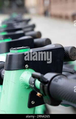 Gros plan du guidon d'un scooter électrique vert. Ville floue en arrière-plan. Véhicules urbains de transport personnel à louer Banque D'Images