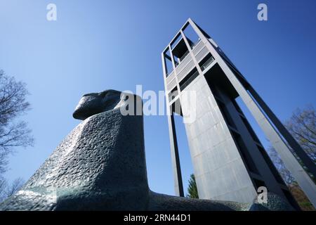 Sculpture du lion du Carillon des pays-Bas Arlington Virginie // ARLINGTON, va — L'une des sculptures stylisées du lion en bronze se trouve à la base du Carillon des pays-Bas avec l'imposante structure en cloche s'élevant de façon spectaculaire derrière elle. Le Carillon néerlandais, un cadeau du peuple néerlandais aux États-Unis en reconnaissance de l'aide américaine pendant et après la seconde Guerre mondiale, comporte 50 cloches et a été installé à l'origine en 1954. Le monument, qui a fait l'objet d'une restauration majeure achevée en 2021, est situé dans le parc Arlington Ridge, entre le cimetière national d'Arlington et le monument commémoratif de guerre du corps des Marines. Banque D'Images
