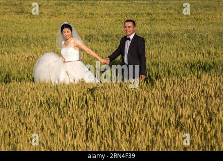 (150519) -- HUAIAN, 19 mai 2015 -- Un couple pose pour des photos de mariage dans le champ de blé du comté de Xuyi, province de Jiangsu, dans l'est de la Chine, le 19 mai 2015. Quelques nouveaux couples d'une entreprise d'alimentation électrique se sont réunis dans un champ de blé pour prendre des photos de mariage de groupe avant leurs mariages. Beaucoup de couples choisissent de se marier le 20 mai de ces années, car la prononciation de 520 sonne comme je t'aime en chinois.) (mt) CHINA-JIANGSU-HUAIAN-WEDDING PHOTO (CN) ZhouxHaijun PUBLICATIONxNOTxINxCHN 150519 Huaian Mai 19 2015 un COUPLE pose pour des photos de mariage dans le champ de blé dans le comté de Xuyi est Chine S Jiangsu province Banque D'Images