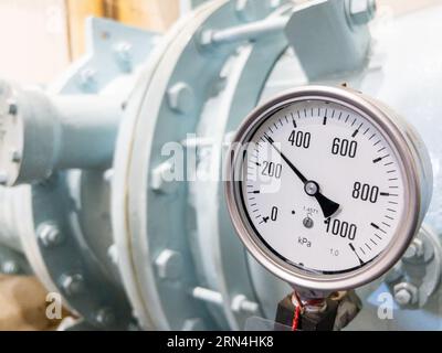 Gros plan de la grande jauge à cadran sur la conduite d'eau pour mesurer la pression de l'eau du robinet dans l'installation d'alimentation en eau, vue de police avec l'espace de copie. Banque D'Images