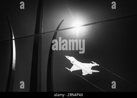 F-16 Fighting Falcon gravure au mémorial de l'US Air Force, Arlington. Photographie en noir et blanc montrant l'avion gravé en vol sur fond des flèches du mémorial. Banque D'Images
