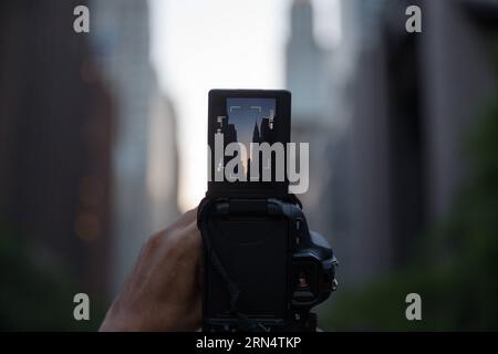 (150531) -- NEW YORK, 30 mai 2015 -- Un homme attend pour prendre des photos de Manhattanhenge à Manhattan, New York, États-Unis, le 30 mai 2015. Les touristes, les résidents et les navetteurs ont attendu pour prendre des photos de l'effet connu sous le nom de Manhattanhenge, mais ont été contrecarrés par les nuages samedi. Le Manhattanhenge se réfère à la circonstance deux fois par an pendant laquelle le soleil couchant s'aligne précisément avec les rues est-ouest de l'arrondissement de New York City de Manhattan. U.S.-NEW YORK-MANHATTANHENGE LixMuzi PUBLICATIONxNOTxINxCHN 150531 New York Mai 30 2015 un homme attend de prendre des photos de Manhattanhenge dans le Ma Banque D'Images