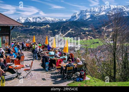 Terrasse ensoleillée de la Martinshuette avec vue sur la vallée, le village, les montagnes de Wetterstein et Karwendel, Garmisch-Partenkirchen Banque D'Images