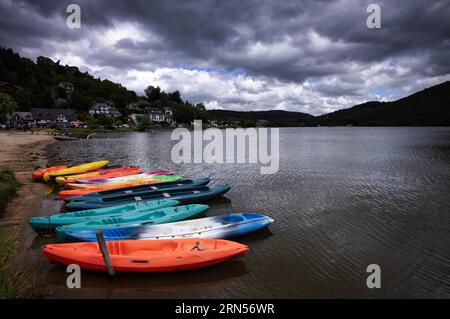 Bateaux colorés, canoës, couchés sur le lac Chambon, lac volcanique, Chambon-sur-Lac, département du Puy-de-Dôme, région Auvergne-Rhône-Alpes, France Banque D'Images