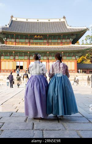 Jeune femme dans le hanbok traditionnel devant la salle d'audience Injeongjeon Hall, avec des touristes, Palais Changdeokgung, Jongno-gu, Séoul Banque D'Images