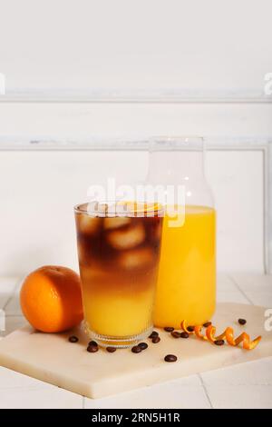 Verre de savoureux espresso orange et bouteille avec jus sur la table Banque D'Images