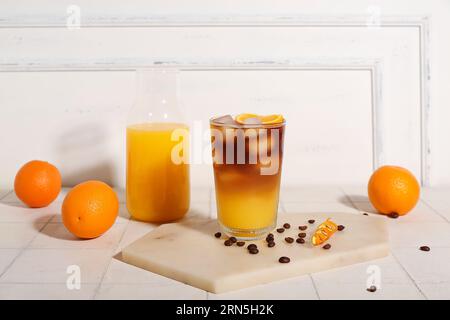 Verre de savoureux espresso orange et bouteille avec jus sur la table Banque D'Images