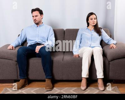 Femme masculine en colère assise canapé Banque D'Images